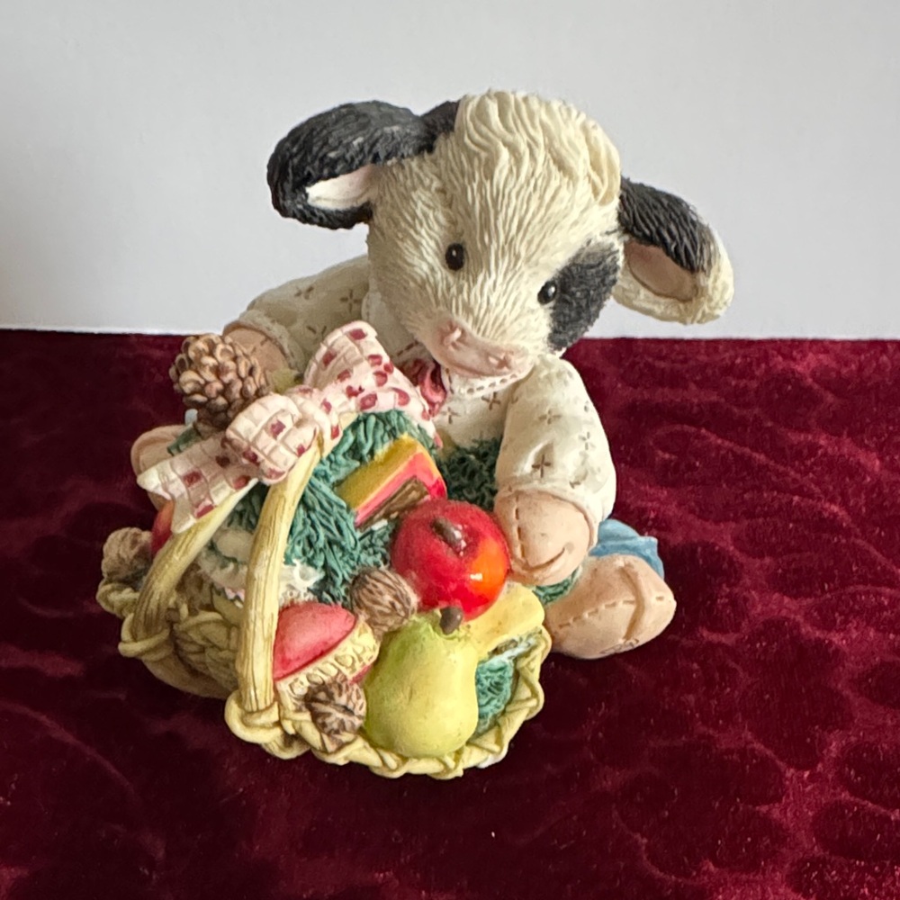 Cow Figurine with Basket filled with fruits, cheese and a small pinecone.